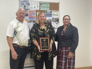 Andres Tobar (left), SEEC Executive Director, and Board Chair Sally Dias-Wells (right) present Ms. Frantz with the Emily DiCicco Humanitarian A